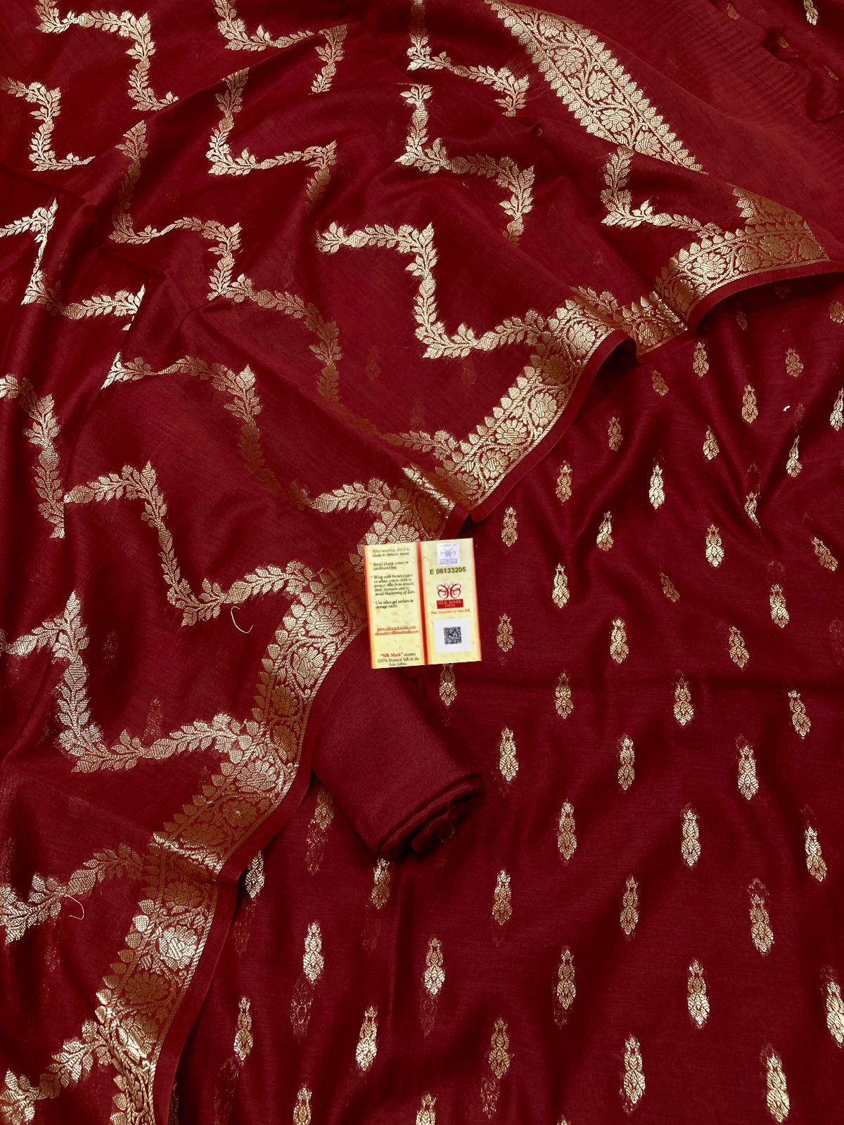 Red fabric with gold patterns and a visible tag.