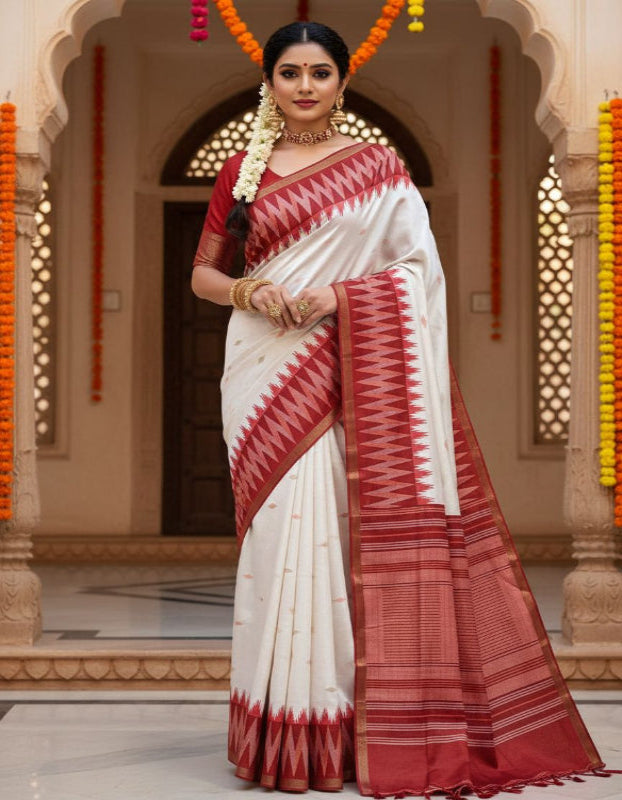 Woman wearing a white and red saree in an ornate indoor setting