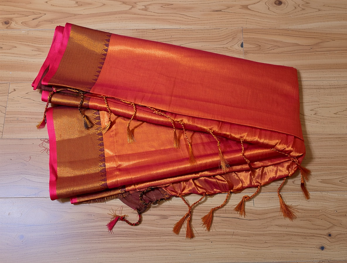 Orange and pink saree with tassels on a wooden floor