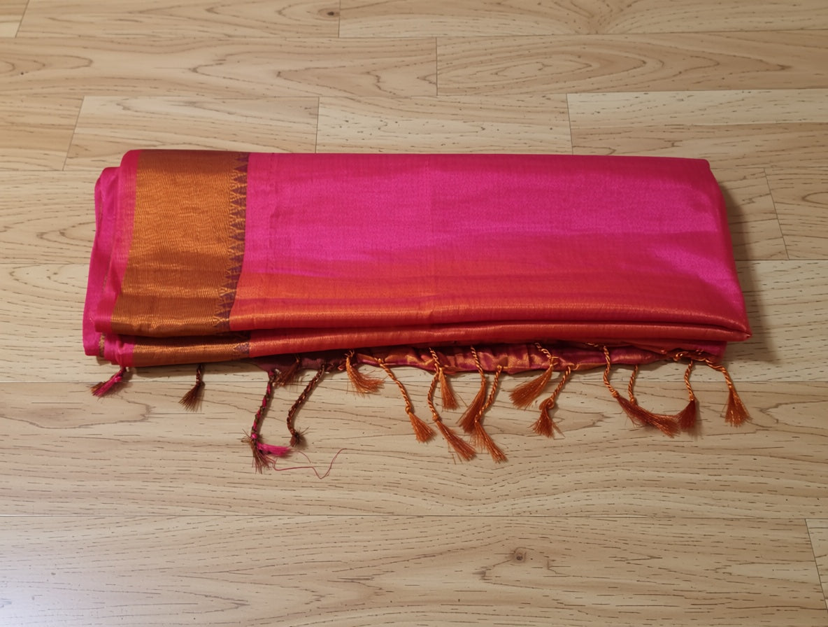 Pink and brown fabric with tassels on a wooden floor